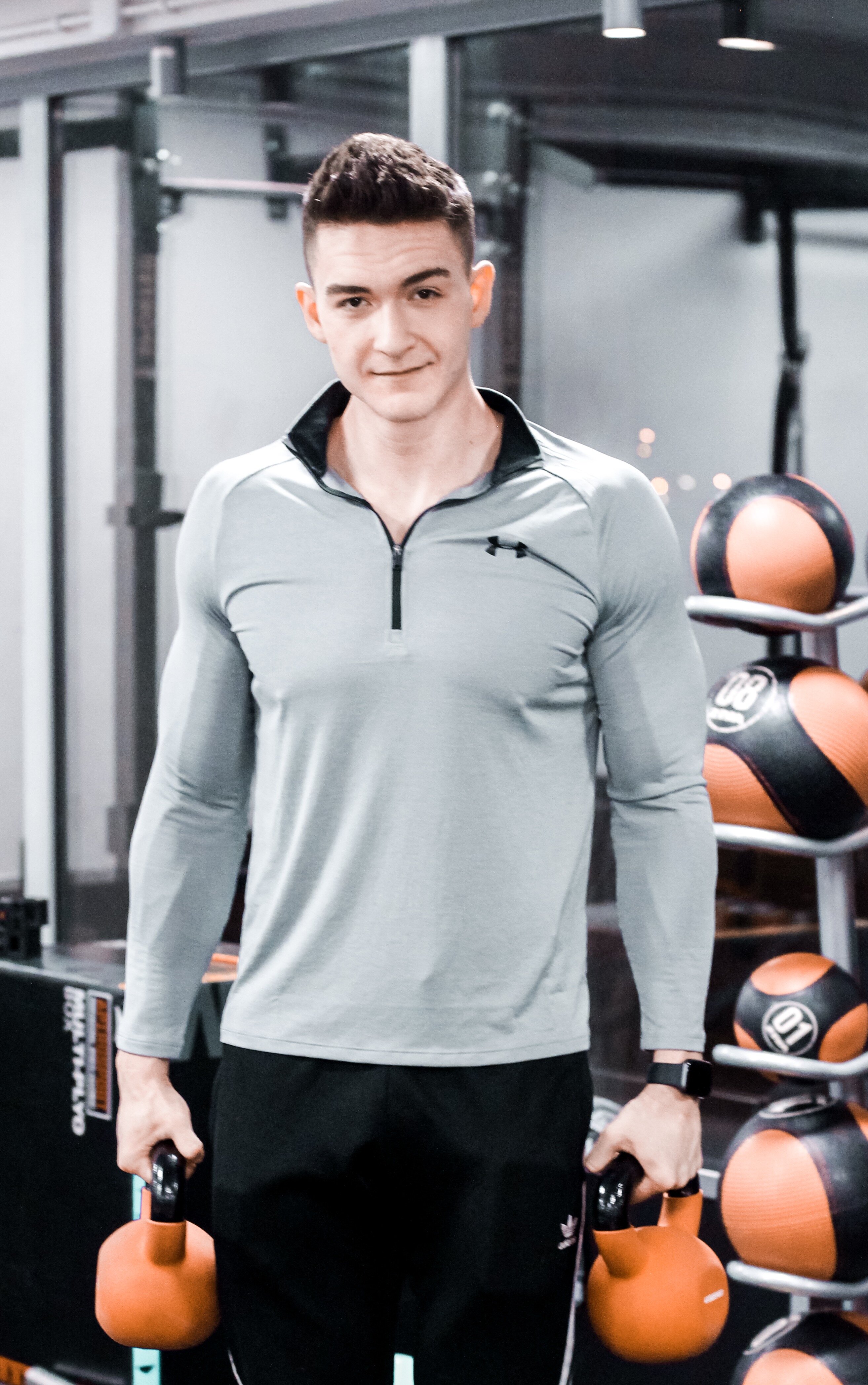 Trening kettlebell - Amadeusz Majcher z odważnikami kulowymi w rękach.